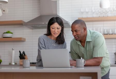 Couple looking at laptop screen on kitchen island
