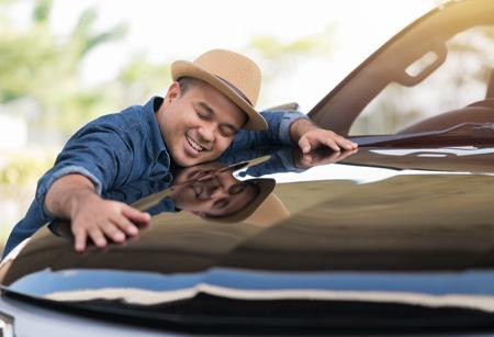 Man smiling and hugging vehicle